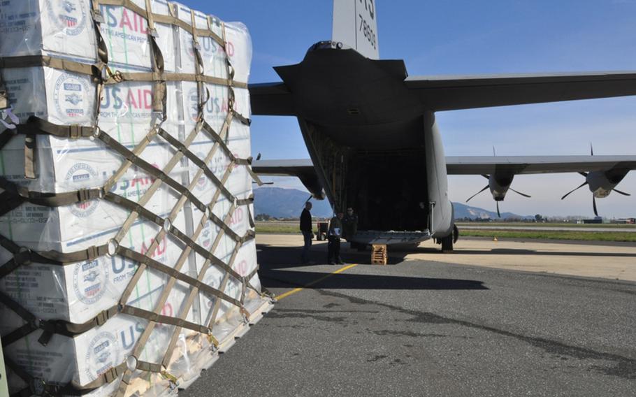 U.S. Agency for International Development boxes containing collapsible water jugs, blankets and plastic sheeting are loaded onto a C-130 transport plane, part of Ramstein Air Base, Germany's 37th Airlift Squadron. 