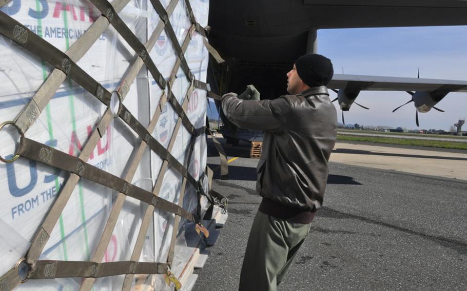 Airman 1st Class Sandy Lee, of the 37th Airlift Squadron, secures humanitarian supplies before loading them onto a C-130 transport plane. The cargo was loaded at Pisa, Italy, where the USAID houses materials at nearby Camp Darby.