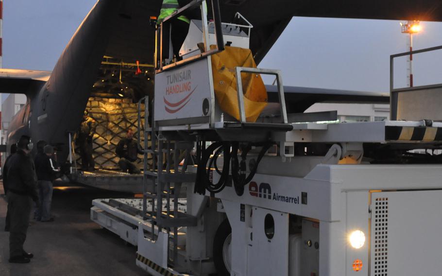 Airmen from the 37th Airlift Squadron and the 435th Airlift Mobility Squadron slide a palette of supplies from the U.S. Agency for International onto a forklift at Tunisia’s Djerba Zarzis airport.