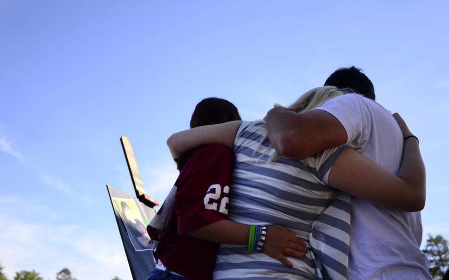 Ramstein High School students, from left to right, Mia Hegi, Samantha Oddo and Anthony Zaferis, comfort one another during an informal gathering to remember Brendon Holtzen, a senior at the school, who died in a car crash Wednesday night.