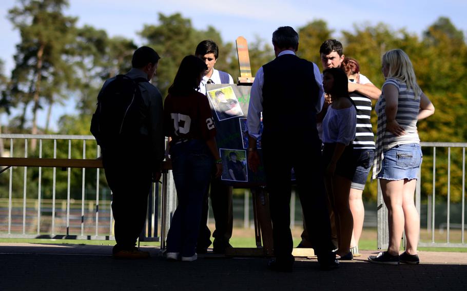 Ramstein High School students and the school psychologist, Terry Arbuckle, stand around a board with photographs of Brendon Holtzen during an informal gathering to remember the 17-year-old senior, who was killed Wednesday evening in a car crash near Ramstein. 