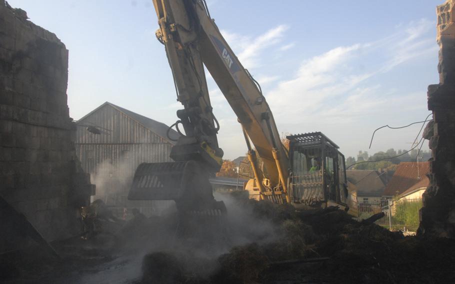 A worker removes smoldering debris from the remnants of a burned hay loft in Kulmain, Germany, on Oct. 2, 2012. Two American soldiers were part of a town response to the blaze on Sept. 30, 2012.