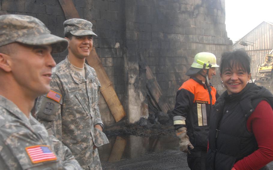 Staff Sgt. Jim Smith, far left, speaks with Spc. Bryan Valenzuela and Monica Wörl in the burned shell of a hayloft belonging to the Wörl family farm in Kulmain, Germany, on Oct. 2, 2013. Smith, 27, and Valenzuela, 21, both residents of Kulmain, and both of the 172nd Separate Infantry Brigade in Grafenwöhr, rushed to the Sept. 30, 2012, fire to help Wörl, 39, and others remove cattle in a barn adjoining the loft. 