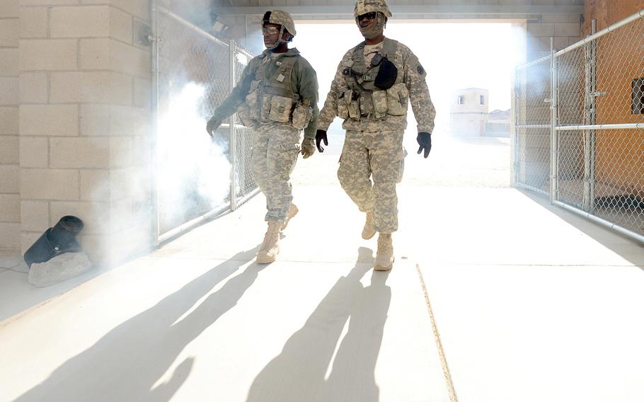 Pfc. Damien Davis, left, and Staff Sgt. James Bates, both of the Operations Group at the National Training Center in Fort Irwin, Calif., walk through a entryway obscured by smoke, Feb. 20, 2013. Their group is documenting the  2nd Brigade Combat Team, 1st Infantry Division from Fort Riley, Kansas as they train at NTC as the first brigade to be aligned with AFRICOM.