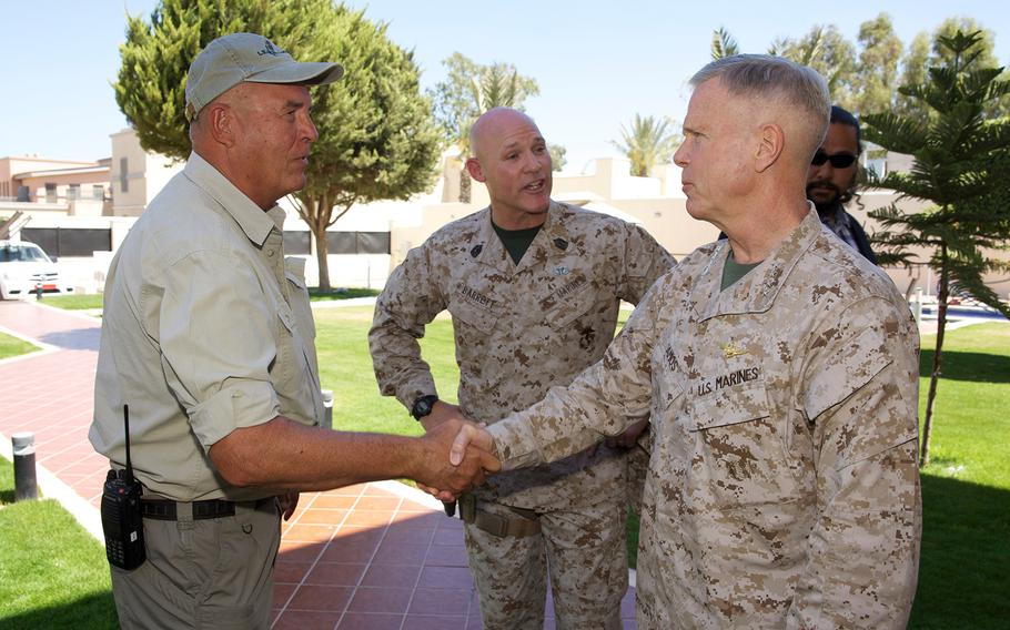 Gen. James F. Amos, commandant of the Marine Corps, greets a civilian worker as Sgt. Maj. of the Marine Corps Micheal P. Barrett, center, stands by during a visit to the U.S. Embassy compound in Tripoli, Libya, on June 16, 2013.