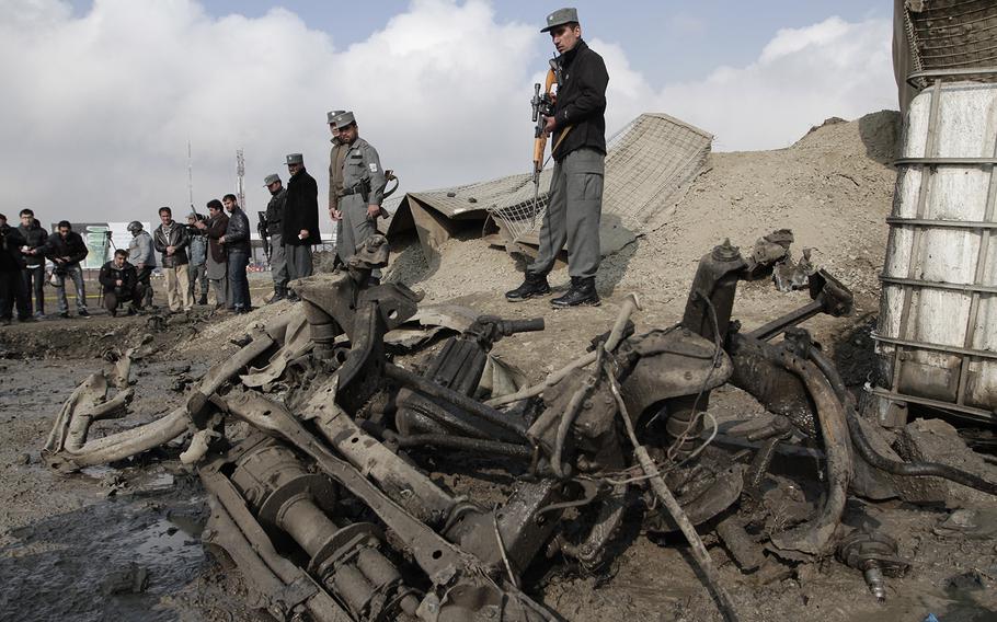 Afghan police examin the remains of a car after a suicide attack near a gate used by NATO troops, in Kabul, Afghanistan, Wednesday, Dec. 11, 2013. The Afghan Interior Ministry says a car bomb has exploded near a gate used by NATO troops in the northern section of the Kabul airport. There were no casualties in the attack.