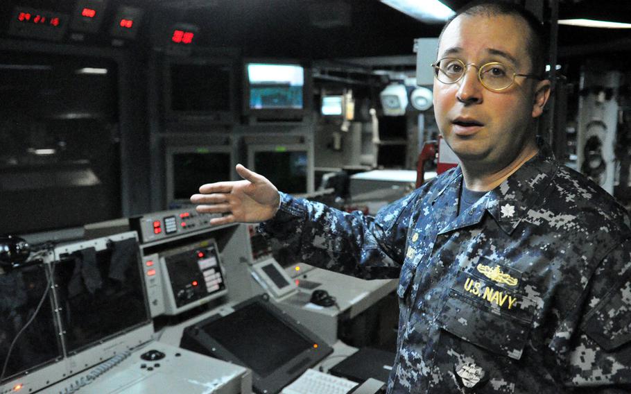 Cmdr. Scott A. Jones, commanding officer of the USS Donald Cook, explains the weapons system terminals inside the ship's Combat Information Center. The Cook, an Arleigh Burke-class guided missile destroyer, arrived at its new home station in Rota last week and is slated to make its first ballistic missile defense patrol in the coming month. 