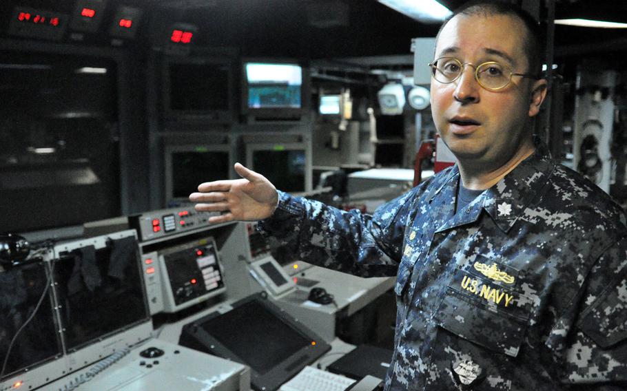 Cmdr. Scott A. Jones, commanding officer of the USS Donald Cook, explains the weapons system terminals inside the ship's Combat Information Center. The Cook, an Arleigh Burke-class guided missile destroyer, arrived at its new home station in Rota last week and is slated to make its first ballistic missile defense patrol in the coming month.