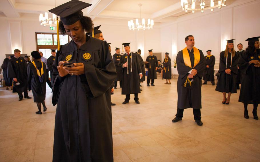 Air Force Master Sgt. Kimberly Johnson, from Goldsboro, N.C., checks her phone before the University of Maryland University College Europe commencement Saturday, May 3, 2014, in Kaiserslautern, Germany.