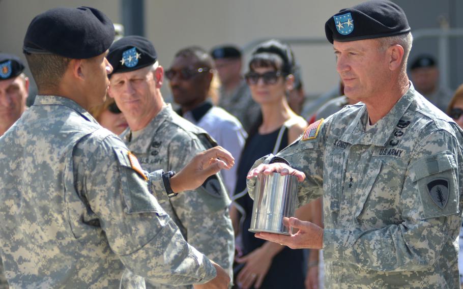 2nd Lt. Michael Bush, left, presents an empty shell casing to Maj. Gen. Richard Longo, U.S. Army Europe deputy commander, at Longo's retirement ceremony on Tuesday, July 22, 2014, at Clay Kaserne in Wiesbaden, Germany. 