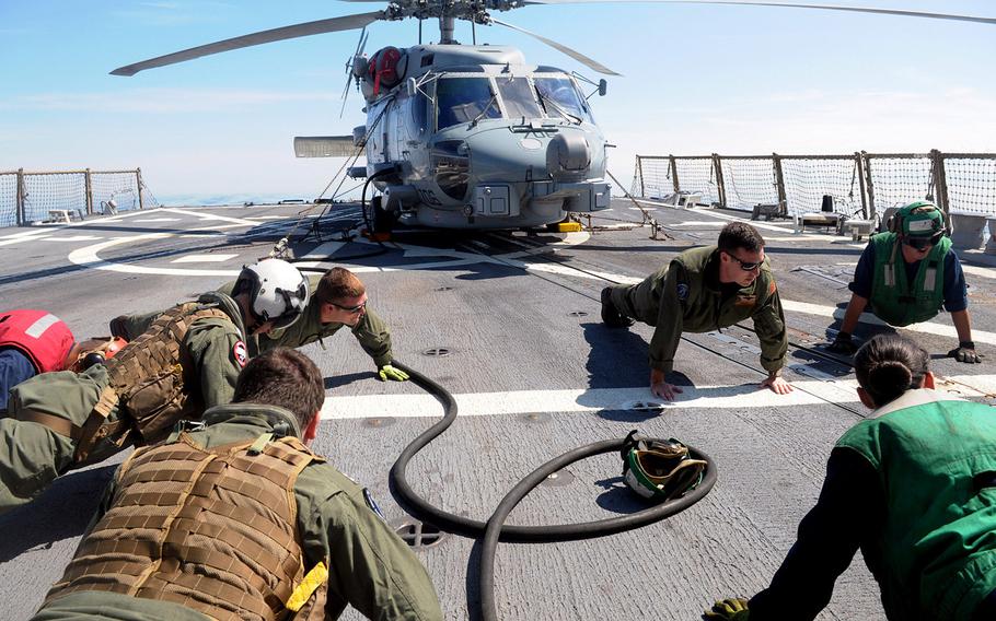 Crew members with the Helicopter Maritime Strike Squadron 72 aboard the USS Oscar Austin perform pushups before a mission in the Baltic Sea on June 27, 2014. The guided missile destroyer Austin is the first warship to visit the Baltic coast since Russia's annexation of Crimea. 