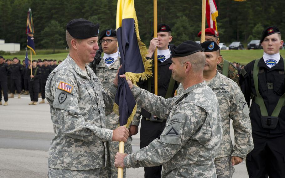 Army Brig. Gen. Christopher Cavoli, right, commander of the Joint Multinational Training Command, hands the guidon to Col. Thomas Mackey, incoming commander of the Joint Multinational Readiness Center, during an assumption-of-command ceremony at Hohenfels, Germany,  Aug. 14, 2014. 

