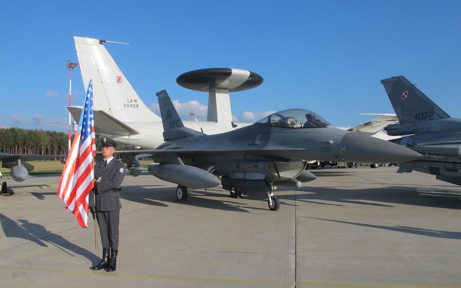 A Polish servicemember stands next to a U.S. F-16, at Lask air base, with a NATO AWACS surveillance aircraft in the background, on Oct. 6, 2014. AWACS are currently deployed over Polish airspace as part of an effort to monitor the security situation in the region.