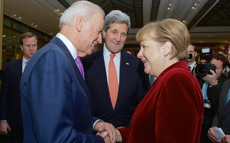 U.S. Secretary of State John Kerry watches as Vice President Joe Biden greets German Chancellor Angela Merkel after she arrived at the Munich Security Conference in Munich, Germany, on February 7, 2015, to deliver a speech and meet with U.S., Ukrainian, and other government officials.