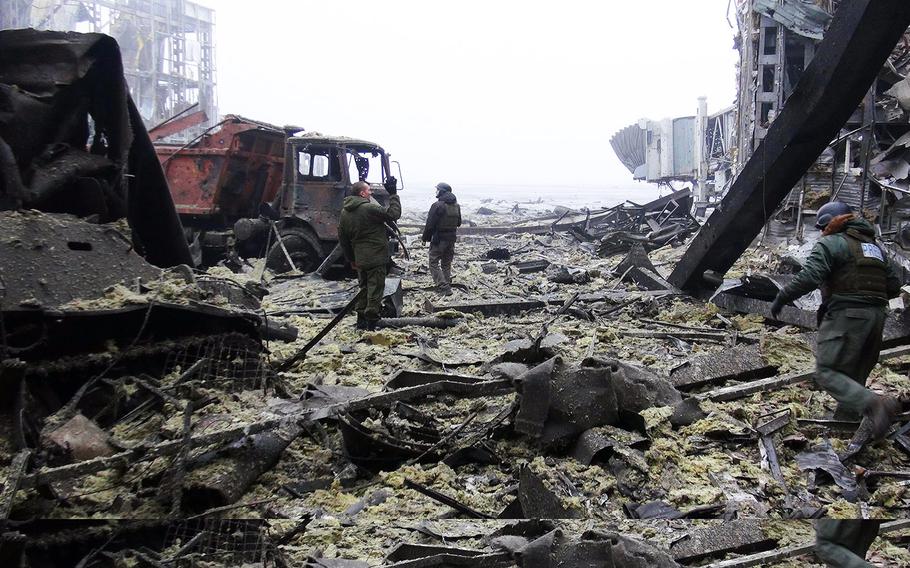 In this file photo from Wednesday, Jan. 21, 2015, Russian-backed rebels clear debris in the destroyed Donetsk airport, which fell to the separatists after weeks of fighting.