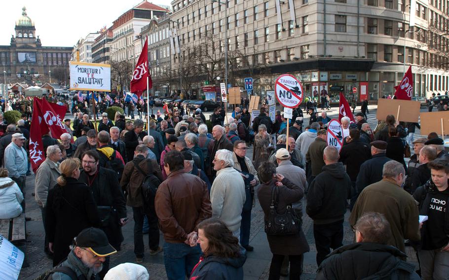 Activists protesting the U.S. Army's convoy operation through the Czech Republic gathered in Prague's Wenceslas Square, Saturday, March 28, 2015. Some carry red flags emblazoned with the logo of the Czech Communist Party.