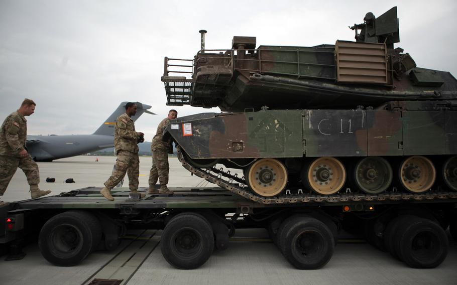 Soldiers talk to the driver of an M1A2 Abrams tank prior to it being loaded onto a C-17 transport plane at Ramstein Air Base in Germany on Saturday, June 20, 2015. The Army is sending two tanks to Bulgaria for a live-fire exercise next week.

