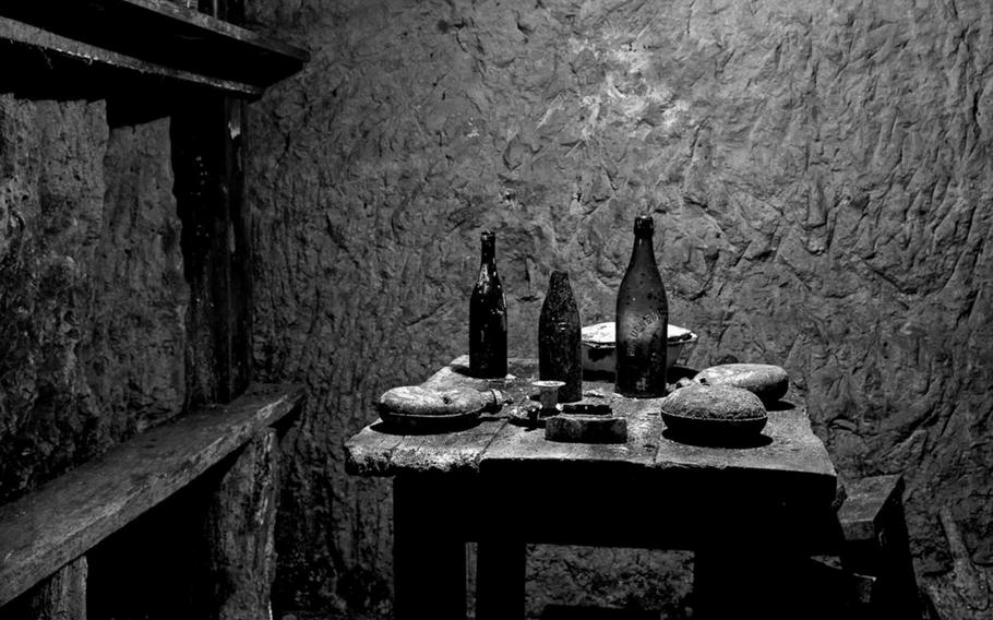 French soldiers' dining area underground with wine bottles, canteens and a serving dish. Photographed 6 December 2011. Vauquois, France.