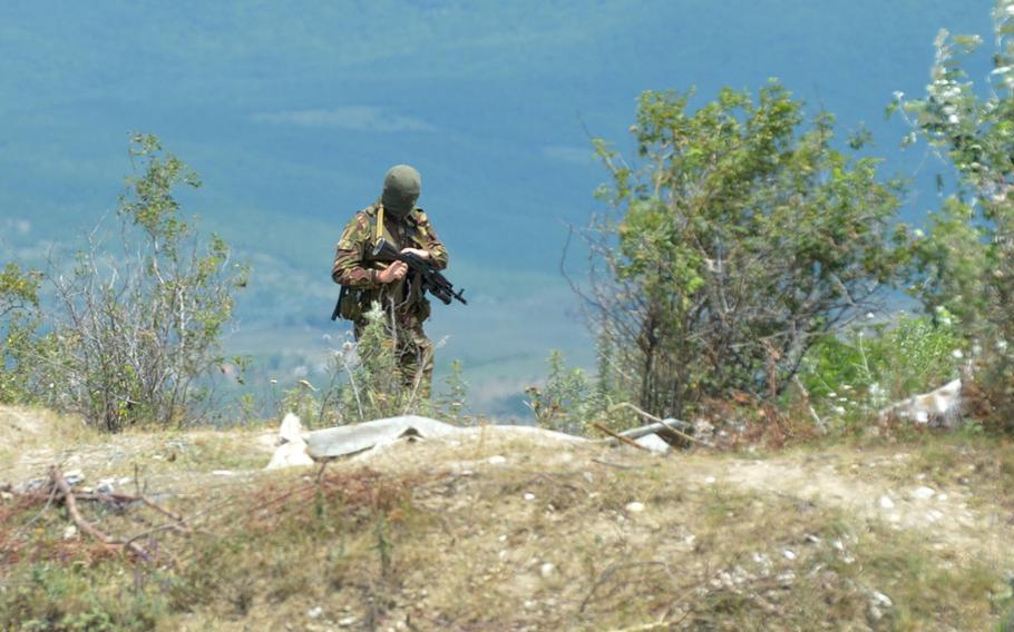 An armed man in uniform and wearing a mask near the boundary between the breakaway enclave of South Ossetia and Georgia, Thursday, July 16, 2015. A Georgian flag was removed on what the South Ossetians claimed was their territory.