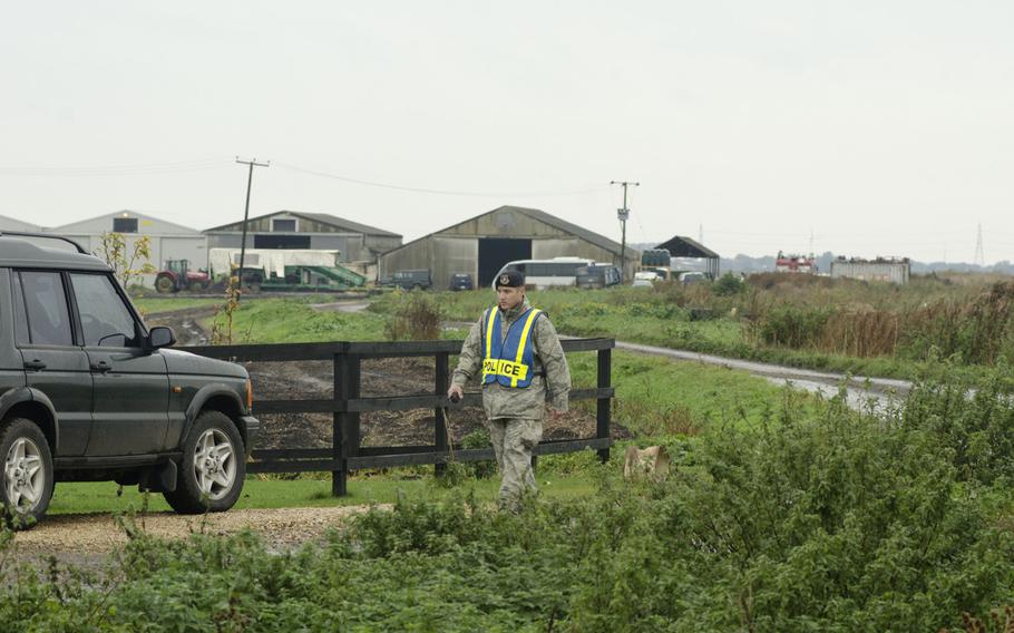 A U.S. airman prepares to man a police roadblock near the scene of an F/A-18 fighter crash in Redmere, England, on Wednesday, Oct. 21, 2015. The plane took off from U.S.-run RAF Lakenheath.

