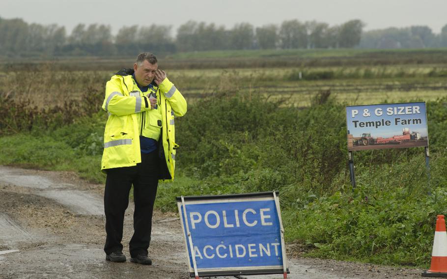 An officer with Cambridgeshire Constabulary guards the entrance to the site of a U.S. F/A-18 crash in Redmere, England, on Wednesday, Oct. 21, 2015. U.S. Air Force and local officials responded to the scene after the plane went down around 11 a.m.
