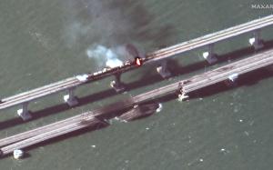 This satellite image provided by Maxar Technologies shows damage to the Kerch Bridge, which connects the Crimean Peninsula with Russia crossing a strait between the Black Sea and the Sea of Azov, and rail cars on fire on Saturday, Oct. 8, 2022. 