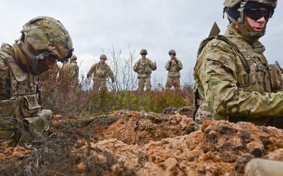 Soldiers of 3rd Squadron, 2nd Cavalry Regiment, stationed at Vilseck, Germany, stand in the trench and place dirt around the 43-pound charge craters to keep them stable so they can be buried in an upright position during a demolition training exercise at Adazi Training Area in Latvia, Jan. 30, 2016.