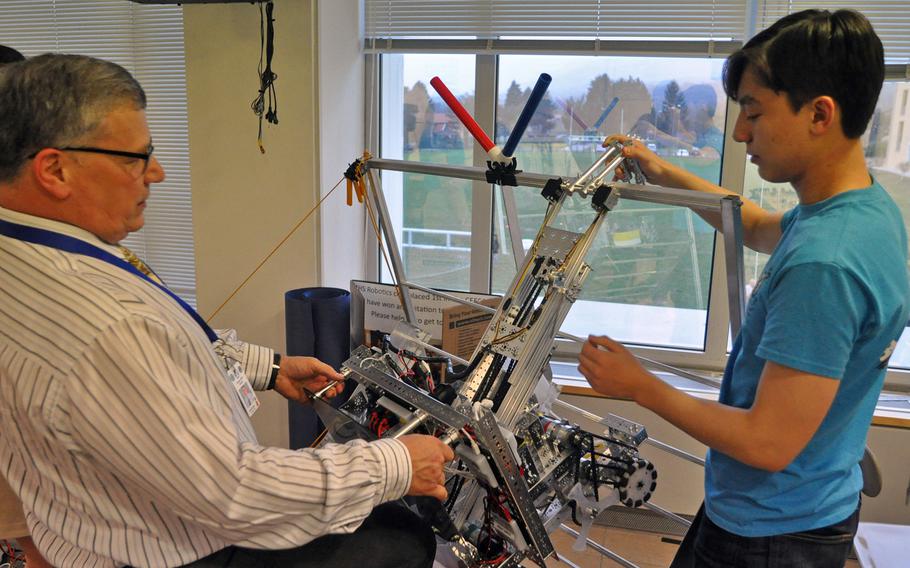 Club adviser Dave Izzo and lead engineer Kyle Kochan demonstrate how a robotic arm is designed to pull the robot up a ramp.

