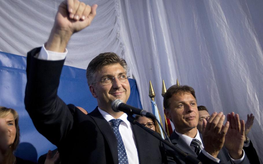 Andrej Plenkovic, leader of the center-right HDZ party, raises a fist in celebration after elections results at the party's headquarters in Zagreb, Croatia, early Monday, Sept. 12, 2016. Initial results of Croatia's early elections showed the conservatives were leading the vote but won't be able to rule on their own, paving the way for another coalition government.