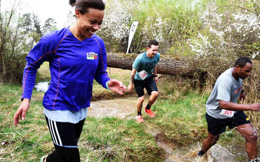 Runners at the annual Grafenwoehr Rugged Terrain Obstacle Run maneuver through logs, puddles and mud at Grafenwoehr, Germany, Saturday, April 15, 2017. 