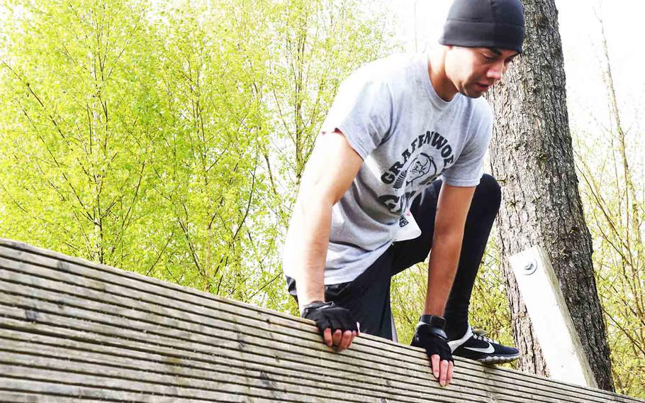 A runner climbs over a wall during an obstacle course and run in Grafenwoehr, Germany, Saturday, April 15, 2017. 