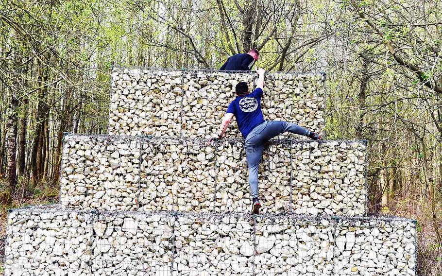 A runner at the annual Grafenwoehr Rugged Terrain Obstacle Run reaches the top of a barrier in Grafenwoehr, Germany, Saturday, April 15, 2017. 