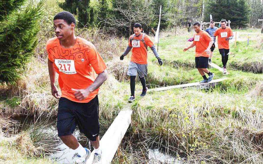 Runners at the annual Grafenwoehr Rugged Terrain Obstacle Run maneuver across beams in Grafenwoehr, Germany, Saturday, April 15, 2017. 