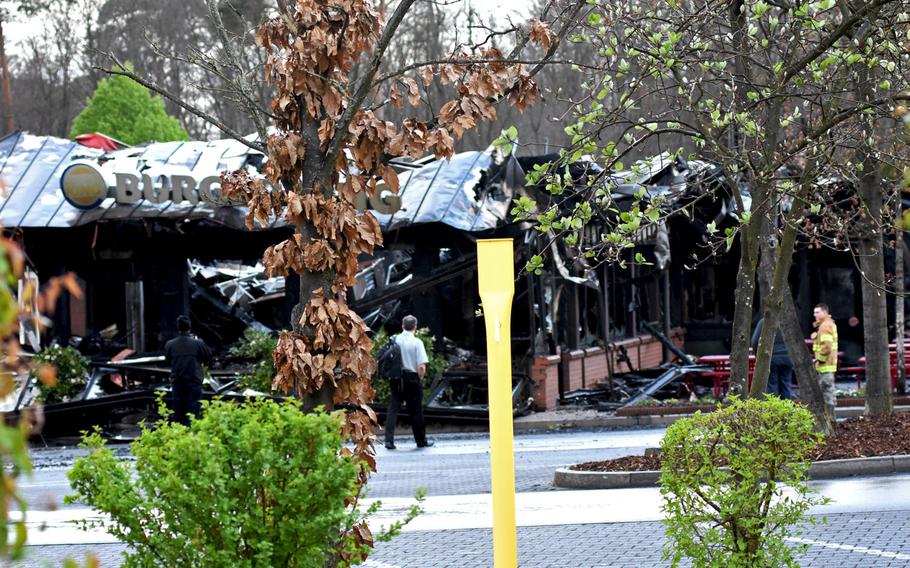 A few people mill about the scene of the Burger King fire on Ramstein Air Base, Germany, on Monday morning, April 17, 2017. Not much remains of the fast food restaurant after it caught on fire on Easter day. The cause is under investigation, though early reports suggest the fire started outside the building.