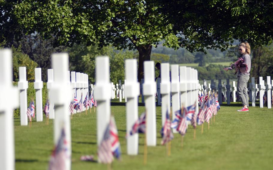 U.S. Air Force Airman 1st Class Brittany Holland places U.S. flags near headstones at the Cambridge American Cemetery and Memorial in Cambridge, England, Friday, May 26, 2017, in preparation for this Memorial Day. 