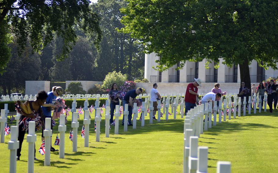 Volunteer U.S. servicemembers, veterans and the local British community members place flags among headstones at the Cambridge American Cemetery and Memorial in Cambridge, England, Friday, May 26, 2017, in preparation for this Memorial Day. 