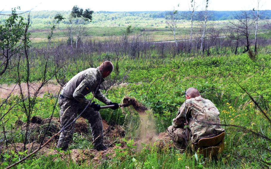 Two Ukrainian soldiers dig a fighting hole during a mock defensive battle in conjunction with the Joint Multinational Training Group-Ukraine, in Yavoriv Ukraine, June 29, 2017. 
