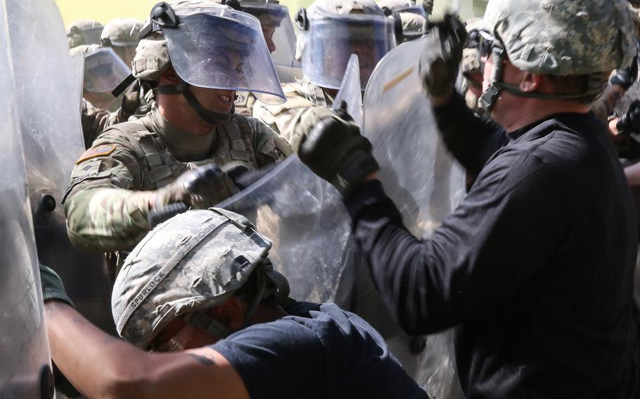 A paratrooper of the 3-319th Airborne Field Artillery Regiment defends the line from role playing protesters during a Crowd and Riot Control training event that is part of KFOR 23's mission rehearsal exercise at the Joint Multinational Readiness Center in Hohenfels, Germany, Thursday, July 6, 2017.