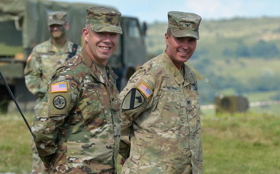 The incoming commander of the 3rd Armored Brigade Combat Team, 4th Infantry Division, Col. Michael Simmering, left, and the outgoing commander Col. Christopher Norrie, laugh at remarks made by division commander Maj. Gen. Ryan F. Gonsalves during the brigades change of command ceremony at the Center for Joint National Training in Cincu, Romania, Saturday, July 15, 2017.