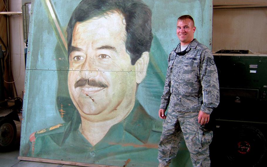 Master Sgt. Jerred Mitchell stands next to a painting of the late former Iraqi president Saddam Hussein while deployed to Iraq in 2008. Mitchell deployed four times during his military career, including twice to Iraq for Operation Iraqi Freedom.

