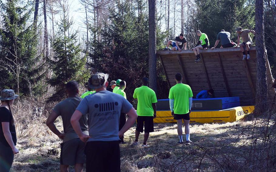 Runners climb over a wall during the Rugged Terrain Obstacle Run, at Grafenwoehr, Germany, Saturday, April 7, 2018. 