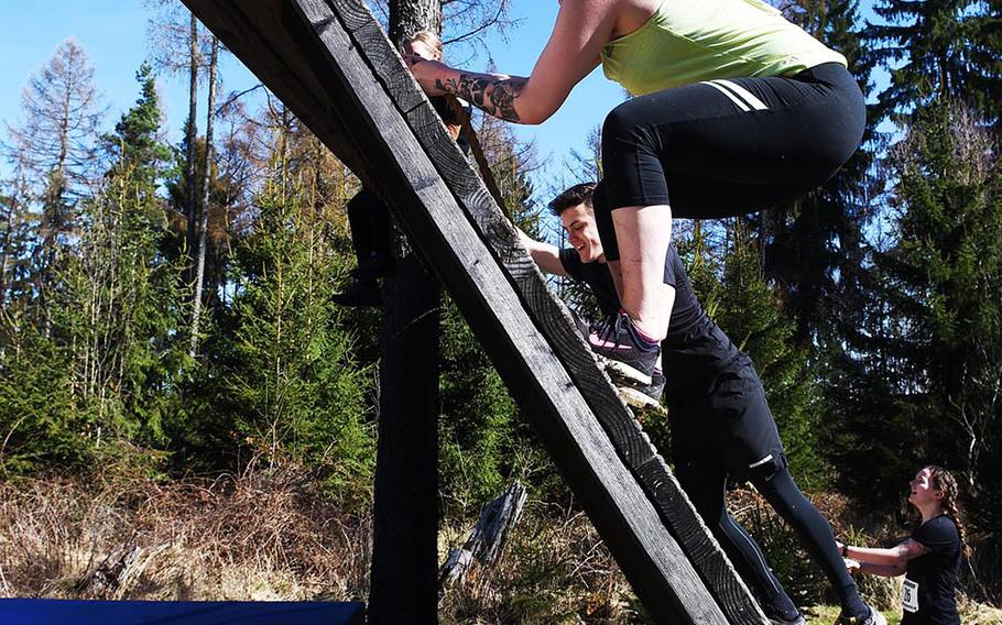 Runners use ropes to climp to the top of an obstacle during the Rugged Terrain Obstacle Run, at Grafenwoehr, Germany, Saturday, April 7, 2018. 
