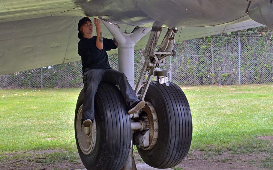 Airman 1st Class Rachael Robinson sits on the wheel of a C-54 Skymaster at the Berlin Airlift Memorial near Frankfurt, Germany, as she make repairs to the aircraft on Saturday, June 23, 2018.  