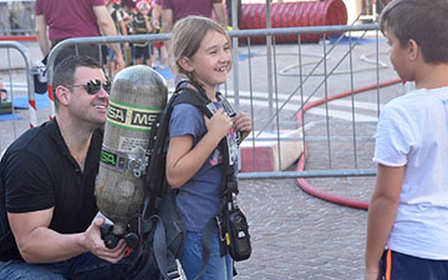 A firefighter with the 31st Fighter Wing fire department helps a child try on a small fire fighters' oxygen tank during the 17th annual Italian-American Frienship Festival that took place Saturday, Sept. 8, 2018, in the city of Pordenone, Italy. 