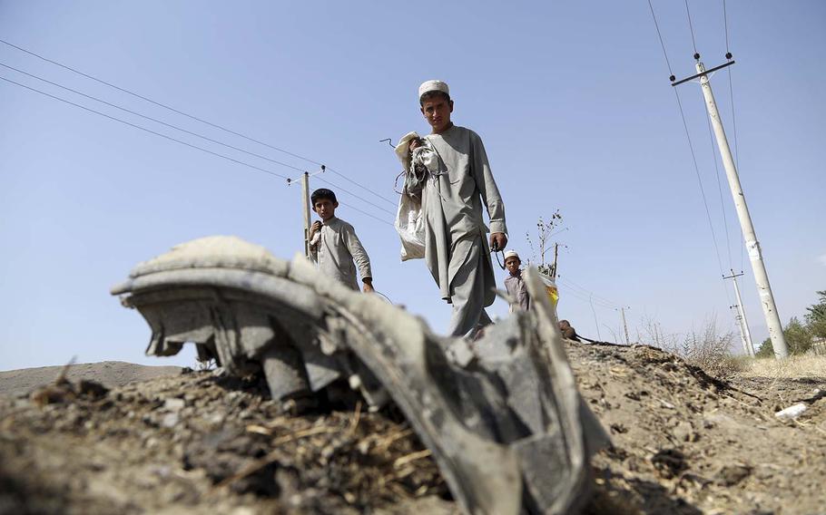 Afghan boys collects the remains of a suicide attacker's vehicle in Kabul, Afghanistan, Wednesday, July 24, 2019. 
