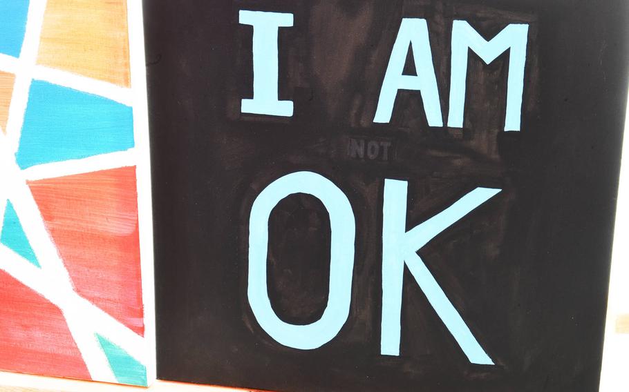 A painting by a U.S. soldier stationed at Tower Barracks appears to read "I am ok," until closer scrutiny shows the hidden word "not". The painting is one of the artistic works by U.S. servicemembers and personnel that were showcased at a market in Grafenwoehr, Germany, Sunday, July 28, 2019. 