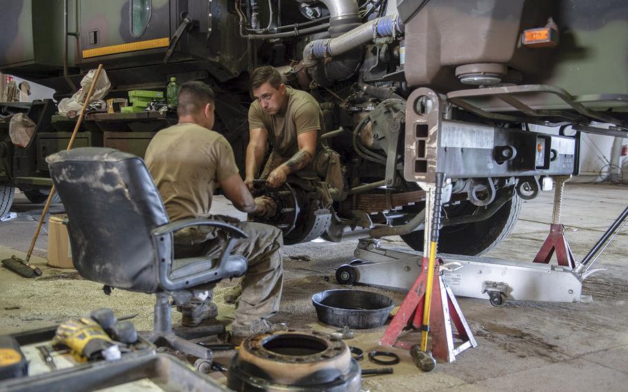 Spc. Sean Hrab, right, and Pfc. Jose Orozzo work on the wheel assembly of a vehicle in the motor pool on a military base in Powidz, Poland, Aug. 27, 2019.

