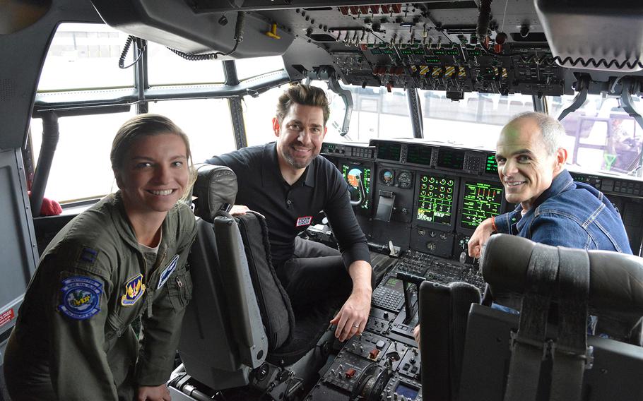 American actors John Krasinski, center, and Michael Kelly sit in a cockpit with Capt. Korie Roberts, 37th Airlift Squadron instructor pilot, during a tour of  Ramstein Air Base, Germany, Oct. 15, 2019. 