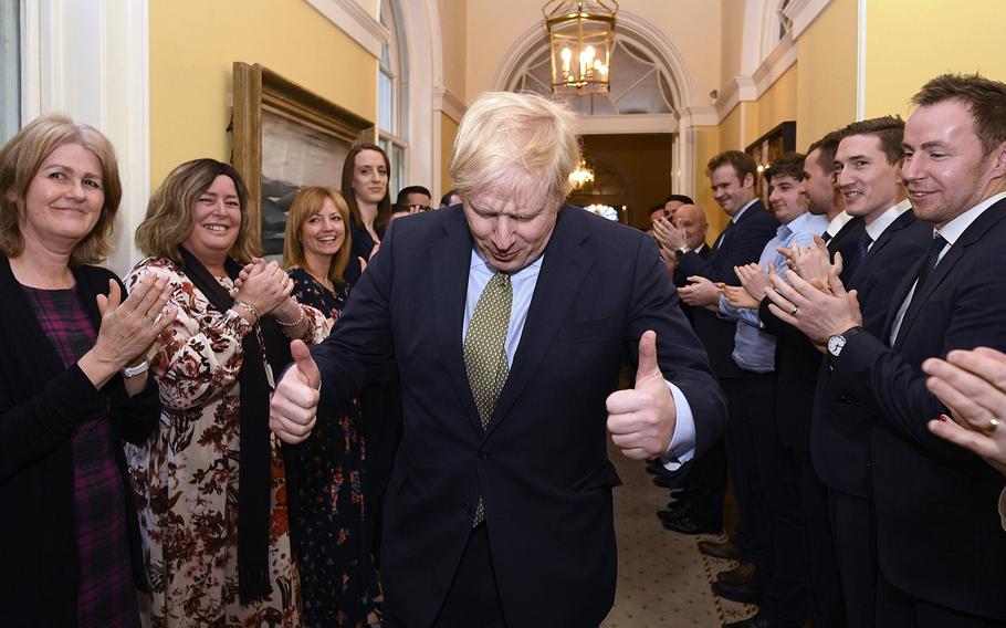 Britain's Prime Minister Boris Johnson is greeted by staff as he returns to 10 Downing Street, London, after meeting Queen Elizabeth II at Buckingham Palace and accepting her invitation to form a new government, Friday Dec. 13, 2019. 