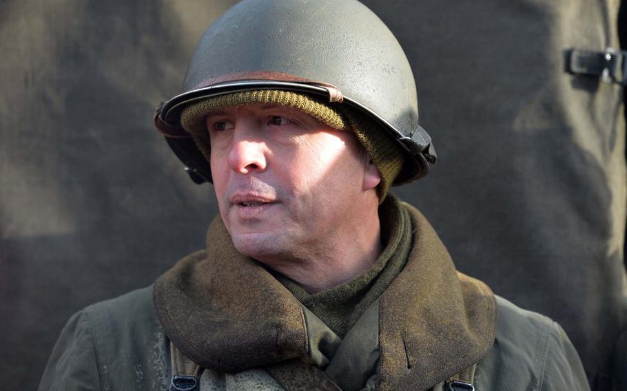 Dressed in World War II-style garb like those worn 30th Infantry Division, Curtis Rhymer, from Kaiserslautern, Germany, talks about the Battle of the Bulge, while visiting Bastogne Barracks in Bastogne, Belgium, during commemorations marking the 75th anniversary of the Battle of the Bulge.